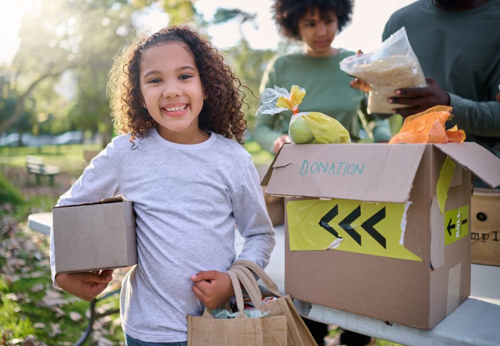 A smiling child holding a box of food.