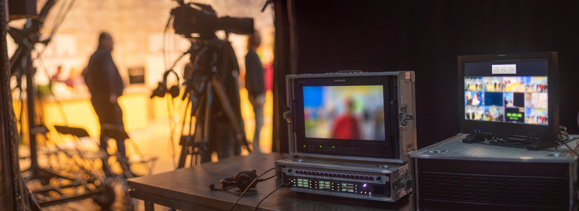 TV studio equipment on a table with an out of focus newsroom in the background